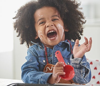 A young child with an afro wearing an apron